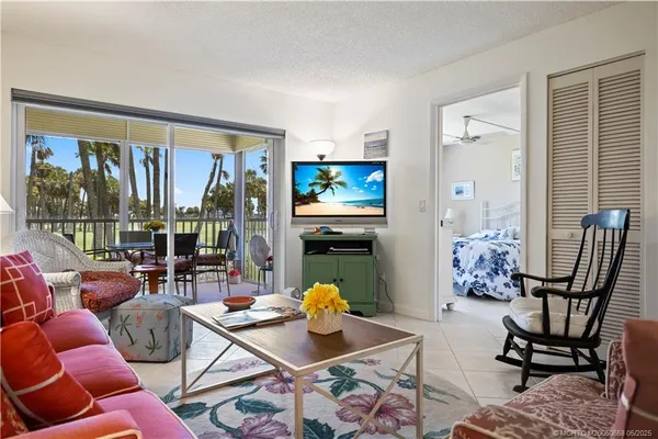 a living room with furniture a floor to ceiling window and potted plant