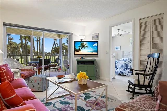 a living room with furniture a floor to ceiling window and potted plant