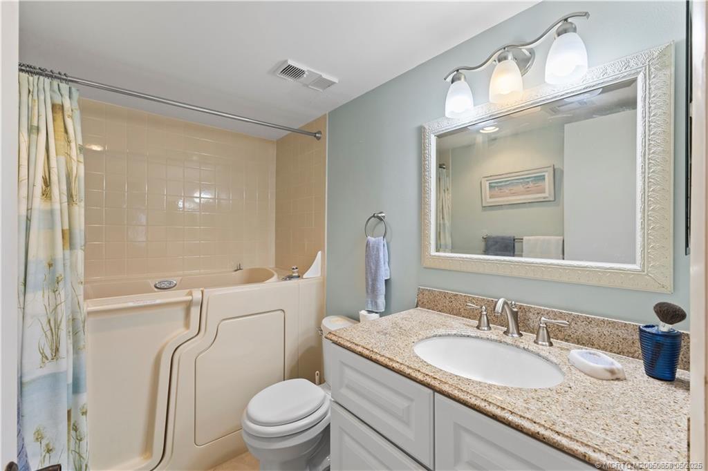 5571 Northeast Gulfstream Way Stuart, FL 34996 - Photo 28 of 40 a bathroom with a granite countertop sink toilet and shower