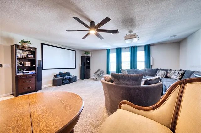 a living room with furniture a ceiling fan and a flat screen tv