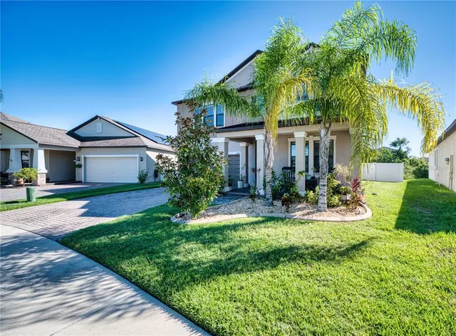 a front view of a house with a yard and potted plants