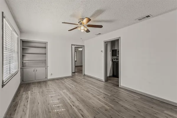 a view of empty room with wooden floor and fan
