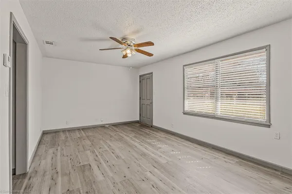 a view of empty room with wooden floor and fan