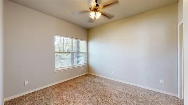an empty room with a window and a fan