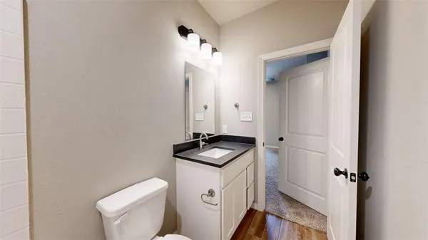 a bathroom with a granite countertop sink and a toilet