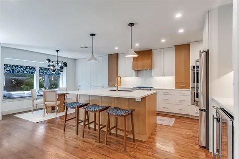 a kitchen with stainless steel appliances a dining table chairs stove and white cabinets