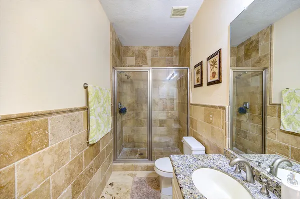 a bathroom with a granite countertop sink a toilet and shower