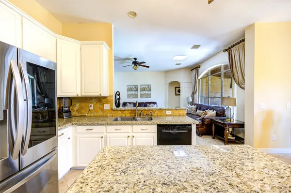 a kitchen with stainless steel appliances kitchen island granite countertop a stove refrigerator and cabinets