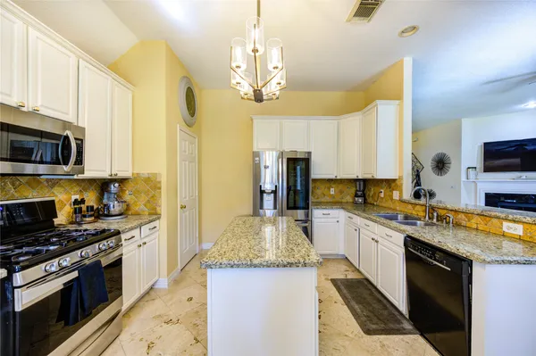 a large kitchen with stainless steel appliances granite countertop a stove top oven a sink dishwasher a dining table and chairs with wooden floor