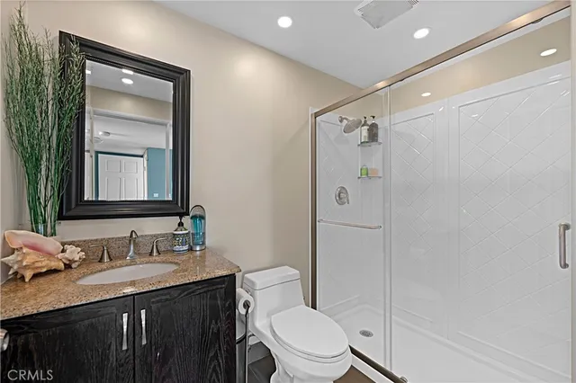 a bathroom with a granite countertop sink toilet a mirror and shower