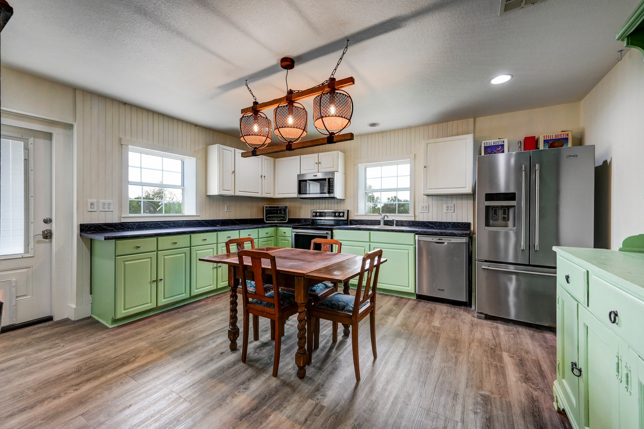6350 Mt Sharp Road, Unit B Wimberley, TX 78676 - Photo 22 of 34 a kitchen with stainless steel appliances granite countertop a sink dishwasher a refrigerator with wooden floor