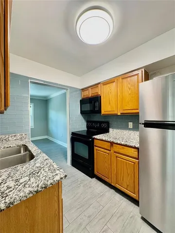 a kitchen with stainless steel appliances granite countertop a sink stove refrigerator and cabinets
