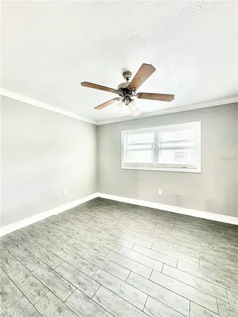 an empty room with wooden floor fan and windows
