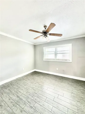 an empty room with wooden floor fan and windows