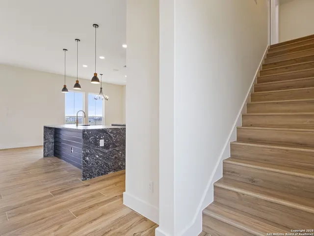 a kitchen with kitchen island granite countertop a stove a sink a center island a refrigerator and a wooden floor