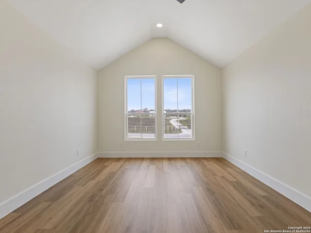 an empty room with wooden floor and a ceiling fan