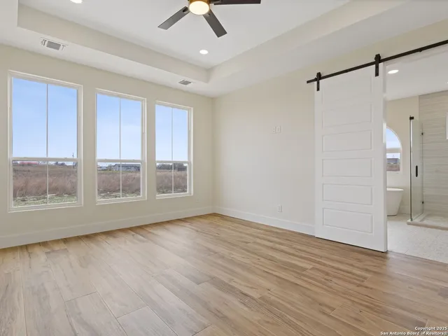 a view of an empty room with wooden floor a ceiling fan and wooden floor