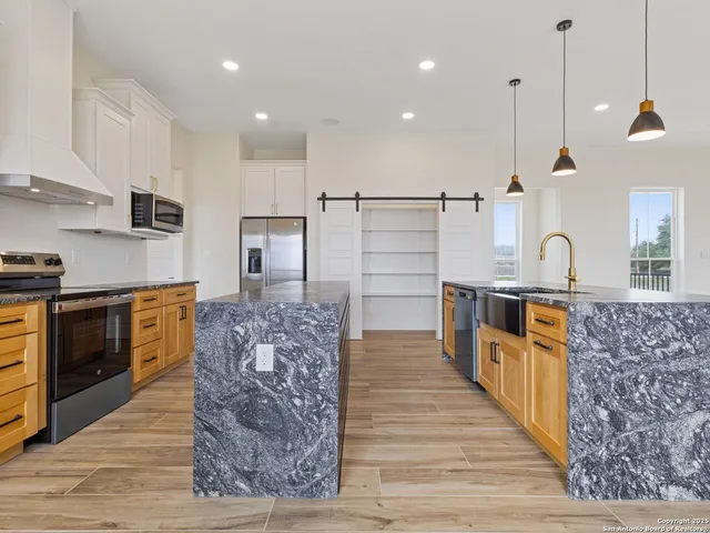 a kitchen with stainless steel appliances granite countertop a sink a stove and a wooden floors