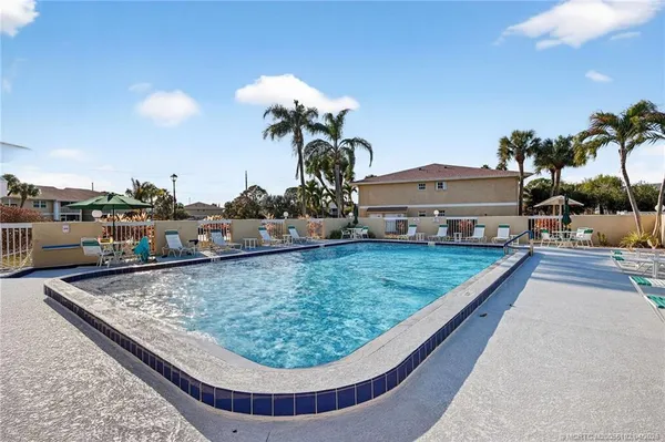 a view of a swimming pool with a lawn chairs under an umbrella