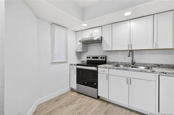 a kitchen with stainless steel appliances granite countertop a stove a sink and white cabinets