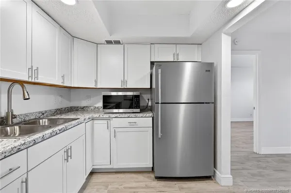 a kitchen with appliances a refrigerator a sink and cabinets