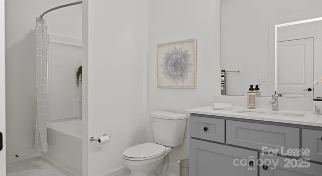 a bathroom with a toilet a sink a mirror a vanity and shower