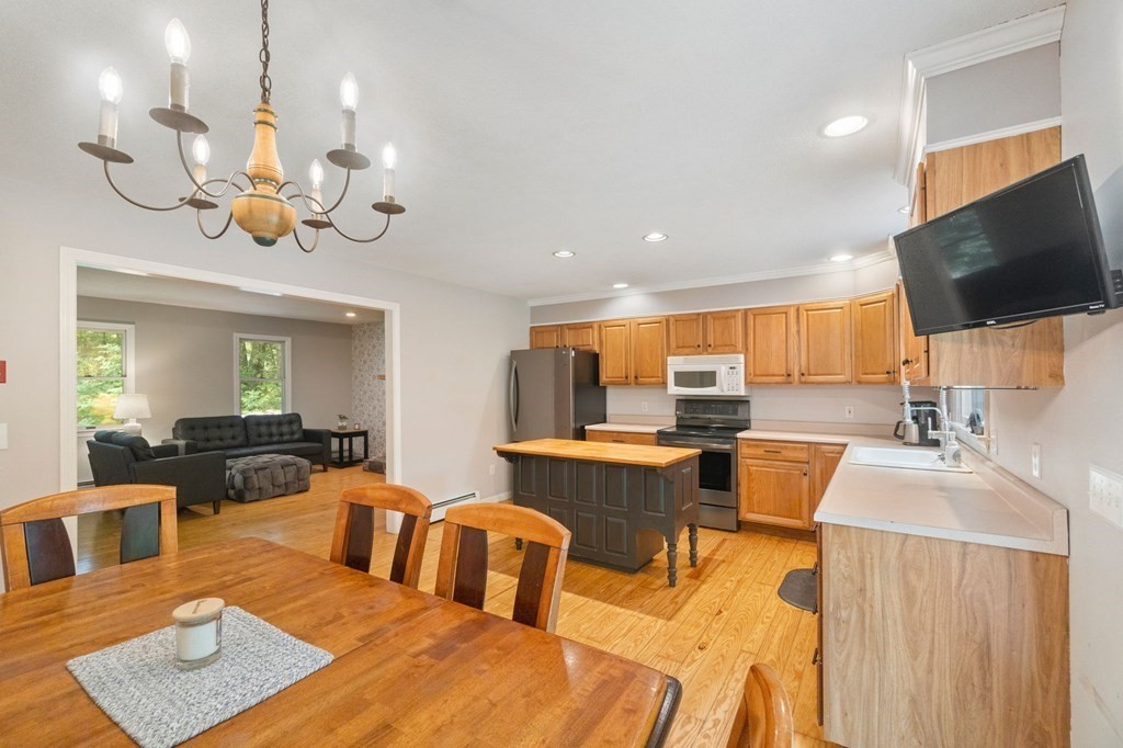 147 Wales Road Monson, MA 01057 - Photo 27 of 41 a view of a dining room and livingroom with furniture wooden floor a rug a potted plant a fireplace and a chandelier