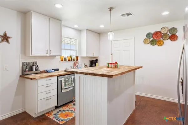a view of a kitchen with kitchen island a sink appliances and cabinets