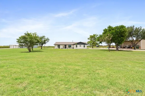 a view of a green field with lots of trees in front of it