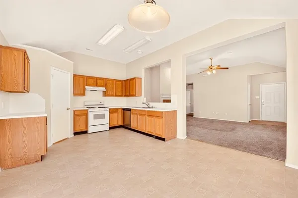 a large white kitchen with cabinets a sink and a stove