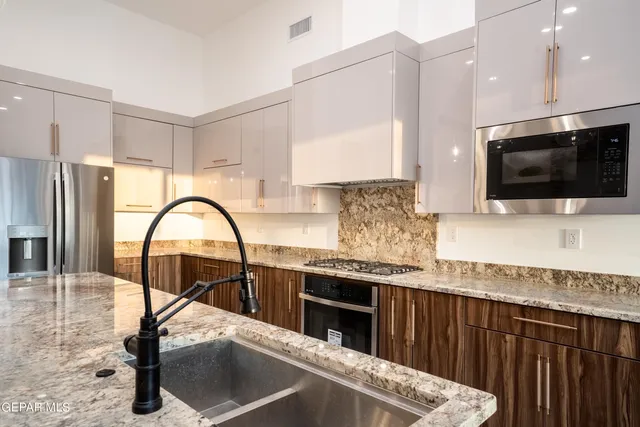 a kitchen with granite countertop a stove a sink and a microwave