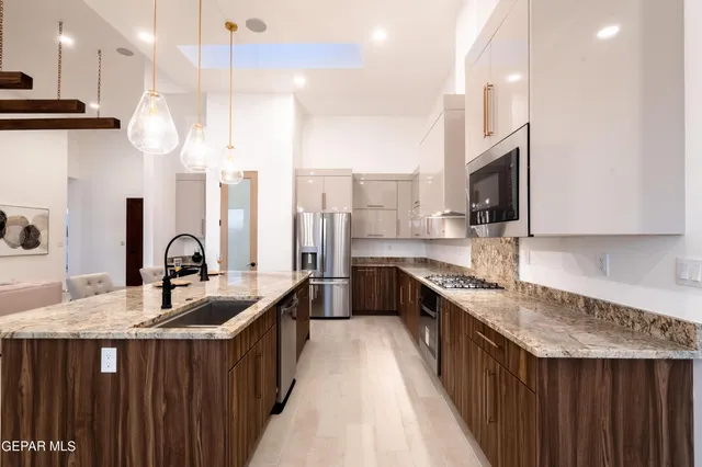 a kitchen with stainless steel appliances granite countertop a sink a stove and a wooden floors