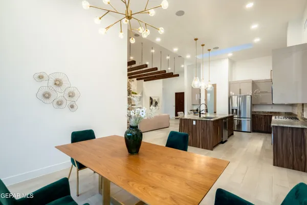 a kitchen with stainless steel appliances kitchen island granite countertop a table chairs and a refrigerator