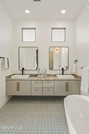 a large white bathroom with a double vanity sink mirror and bathtub