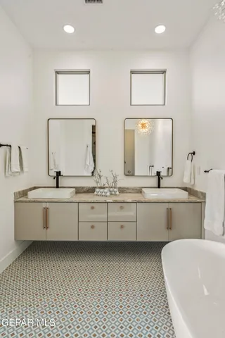 a large white bathroom with a double vanity sink mirror and bathtub