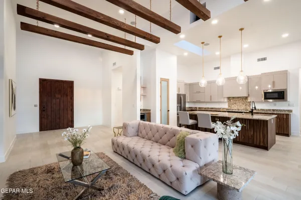 a living room with couches and kitchen view with wooden floor