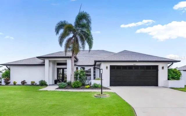 a front view of a house with a garden and palm trees