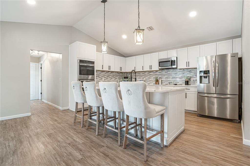 5807 Garfield Road Venice, FL 34293 - Photo 11 of 40 a kitchen with stainless steel appliances a refrigerator a stove a sink and a dining table with wooden floor