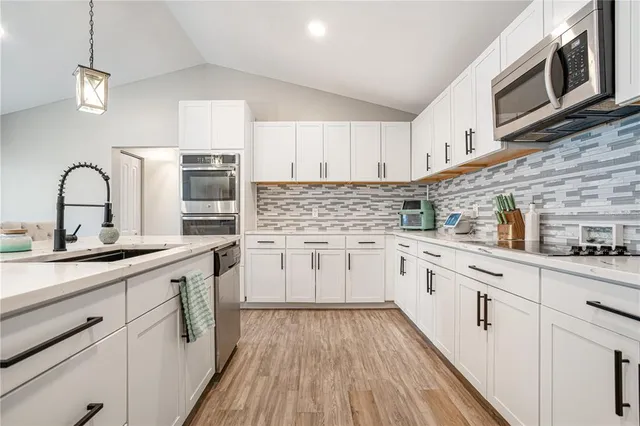 a kitchen with white cabinets a sink a stove and white appliances