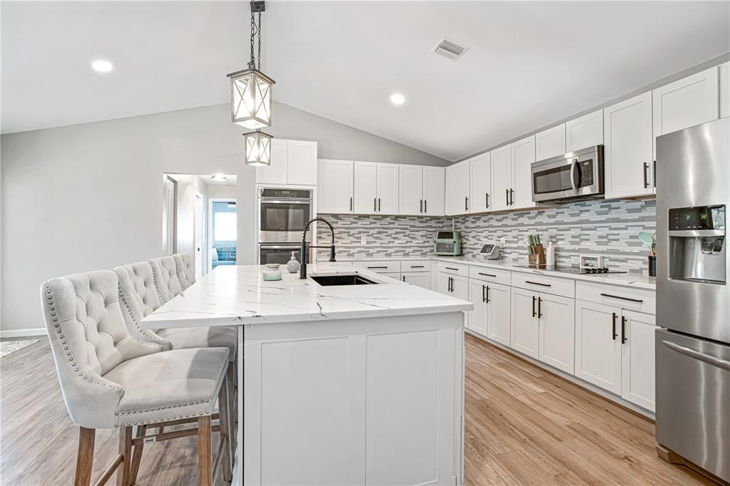 5807 Garfield Road Venice, FL 34293 - Photo 14 of 40 a kitchen with stainless steel appliances kitchen island granite countertop a sink a stove a refrigerator cabinets a dining table and chairs