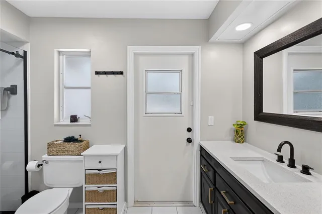 a bathroom with a granite countertop sink toilet and mirror