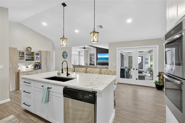 a large kitchen with kitchen island a stove a sink a center island and living room view