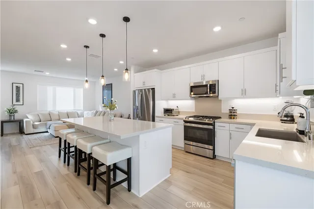 a kitchen with kitchen island a white counter top space a sink stainless steel appliances and cabinets