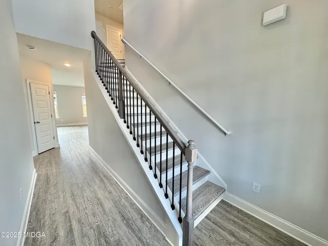 a view of staircase with wooden floor and white walls