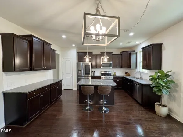 a kitchen with stainless steel appliances kitchen island granite countertop a stove refrigerator and cabinets