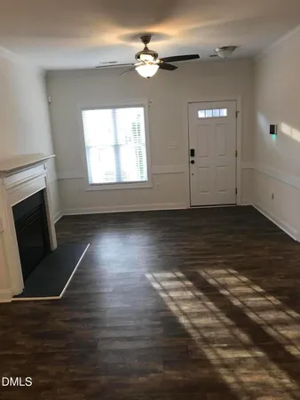 an empty room with wooden floor fireplace and windows