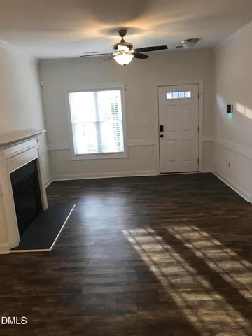 an empty room with wooden floor fireplace and windows