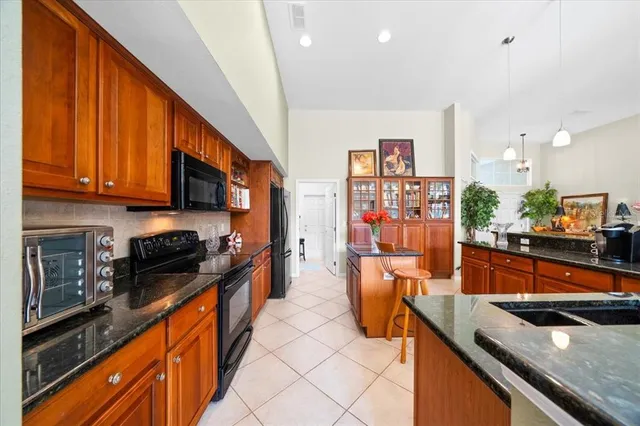 a kitchen with stainless steel appliances granite countertop a sink a stove top oven a counter space and cabinets