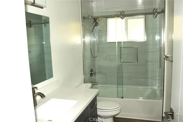 a bathroom with a bathtub shower sink vanity mirror and toilet