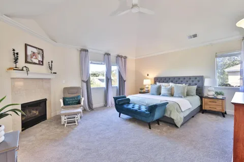 a spacious bedroom with a bed a table and a fireplace